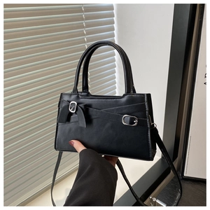 Détail du sac rectangulaire noir mat avec nœud décoratif et boucle argentée