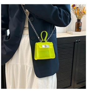 Macro view of neon yellow jelly crossbody bag with silver chain strap and twist-lock detail