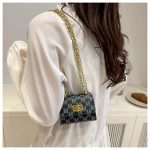 Close-up of a mini monogram chain crossbody bag worn by a model in a minimalist setting