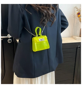 Detail of neon green mini jelly bag with silver clasp and chain on dark suit