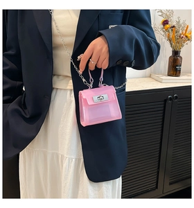 Detalle de mini bolso rosa transparente con cierre plateado y correa de cadena fina