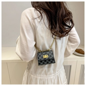 Detailed view of mini crossbody bag with golden chain strap and letter M print on leather