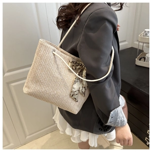 Détail d'un grand sac cabas en paille avec poignées en corde et foulard en soie décoratif