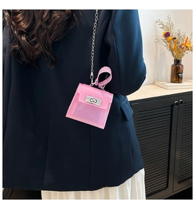 Model wearing a stylish pink mini jelly crossbody bag with metal twist lock and chain