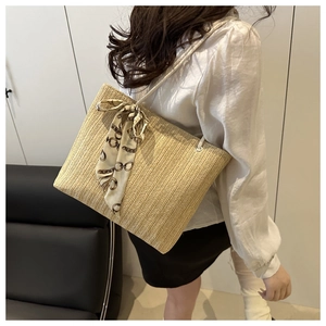 Detail of woven straw tote bag featuring decorative silk scarf and textured chevron pattern