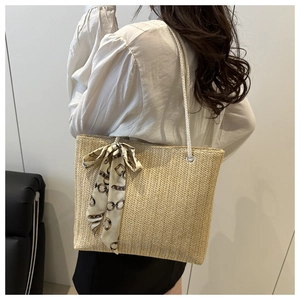 Detail of straw woven tote bag featuring wavy texture and decorative silk scarf detail