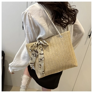 Detailed V-shaped weave of beige straw tote bag with decorative printed silk scarf on handle