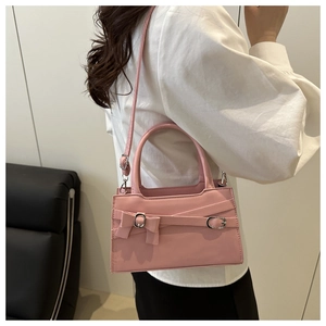 Détail du sac à main rose à nœud avec cuir lisse et boucle métallique élégante
