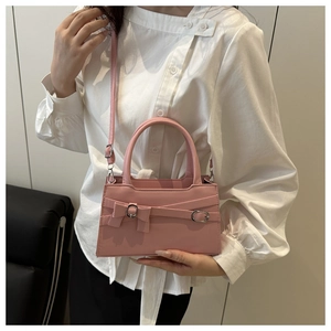 Détail du sac rose à nœud montrant le cuir mat et les boucles métalliques argentées