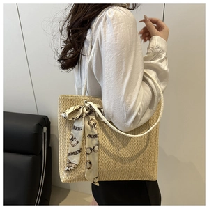 Détail du sac cabas en paille avec tissage en V et foulard en soie sur l'épaule