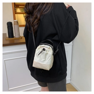Detail of canvas drawstring crossbody bag with contrast paneling shown on a model