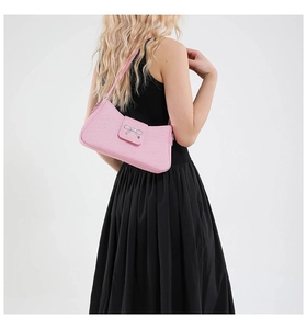 Détail du sac baguette rose avec texture tissée et un nœud en métal argenté