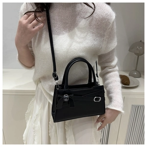 Détail d'un sac à bandoulière en cuir noir avec un nœud délicat et une boucle élégante