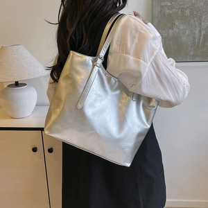 Metallic silver large capacity tote bag shown on a model in a modern interior setting