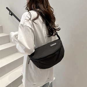Minimalist black nylon crossbody saddle bag for women with fashion label and adjustable strap