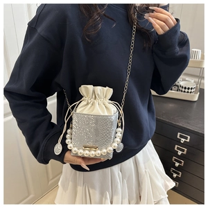 Detail of silver sequin bucket bag with large pearl handle and metallic chain strap
