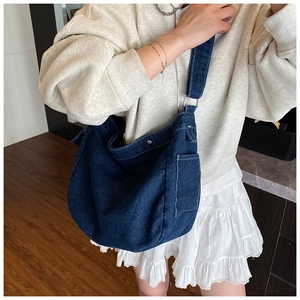 Detail of the blue denim crossbody bag featuring side pocket and metal ring connector