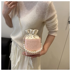 Detail of pink bucket bag with snakeskin texture, pearl handle and gold chain strap