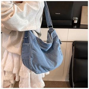 Détail du sac hobo en denim bleu délavé avec poche latérale et boucle en métal réglable