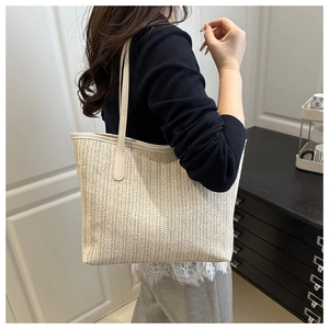 Detail of the herringbone weave texture and cream shoulder straps on the straw tote bag