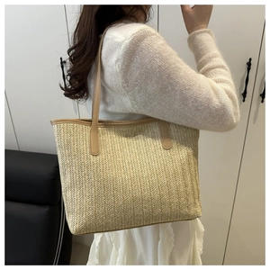Detail of V-shaped woven straw tote bag with brown PU shoulder strap for women