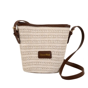 Chic woven straw bucket bag with dark brown leather trim and adjustable shoulder strap