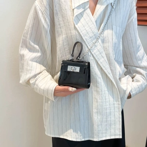 Black glossy mini jelly bag with silver chain strap shown worn by a model