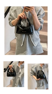 Détail du sac demi-lune noir brillant avec ferrures dorées et lettrage FASHION & BAGS