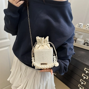 Elegant white snake-embossed bucket bag with pearl handle and golden chain strap