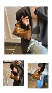 Détail d'un sac demi-lune marron brillant avec lettrage doré et finition en cuir verni élégant
