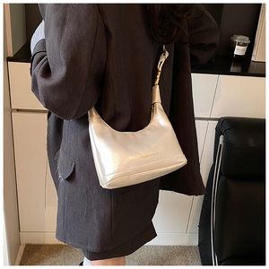 Détail du sac baguette champagne métallisé avec bandoulière chaîne porté par un mannequin