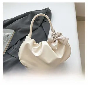 Dettaglio borsa a spalla beige a pieghe con foulard decorativo a motivi geometrici