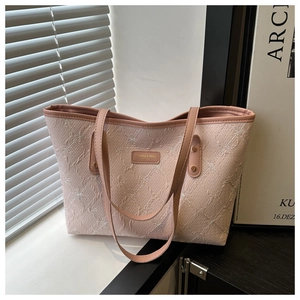 Detail of light pink tote bag featuring intricate 3D bow embroidery and metal logo plate