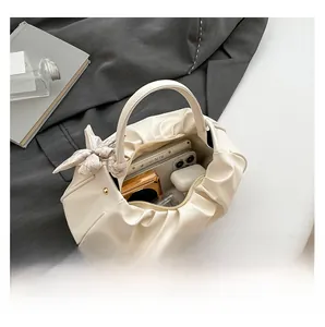 Vista interna della borsa a nuvola beige con foulard in seta e oggetti quotidiani