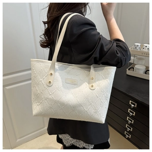 Close-up of beige woven tote bag texture with gold rivets and leather shoulder strap