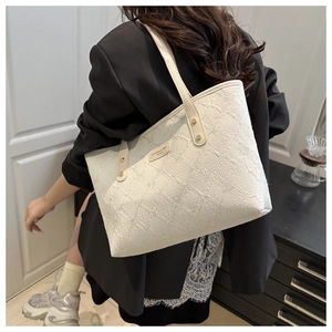 Detail of white tote bag with floral texture and brand tag on a shoulder strap