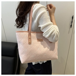Detail of pink tote bag with bow embroidery and shoulder strap shown on a model