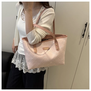 Close-up of pink tote bag with floral texture and metallic brand plaque on shoulder