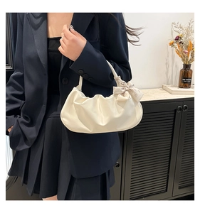 Detail of white pleated cloud bag featuring a decorative bow scarf and soft PU texture