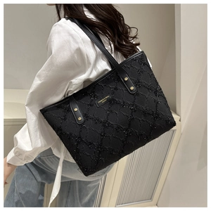 Detailed view of black textured tote bag with sparkling checkered fabric and logo plate
