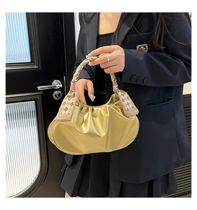 Dettaglio borsa a nuvola oro metallizzato con manico decorato da foulard in seta a scacchi