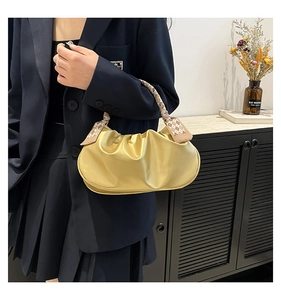 Detail of yellow pleated cloud bag with checkered silk scarf handle on shoulder