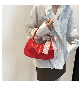 Dettaglio della borsa nuvola rossa a pieghe con finitura lucida e foulard di seta decorativo