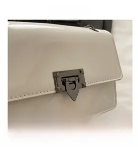 Detailed close-up of the glossy white leather handbag with a metallic buckle lock