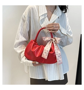 Detail of red cloud pleated handbag with a pink checkered silk scarf tied to the handle