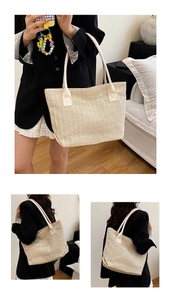 Dettaglio della borsa tote in paglia beige con motivo a spina di pesce e manici bianchi