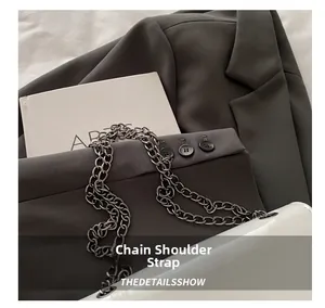 Detail shot of a white chain shoulder strap on glossy faux leather crossbody bag