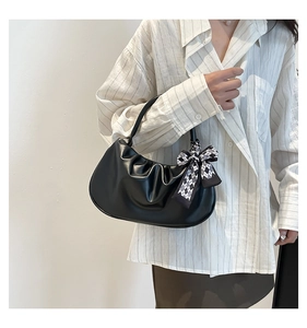 Detail of black pleated cloud bag with a checkered bow tie on a striped shirt