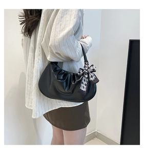 Detail of black pleated cloud bag with checkerboard scarf accent on model's shoulder