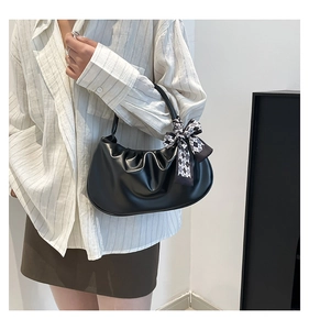 Detail of black pleated cloud bag with a stylish black and white checkered silk bow